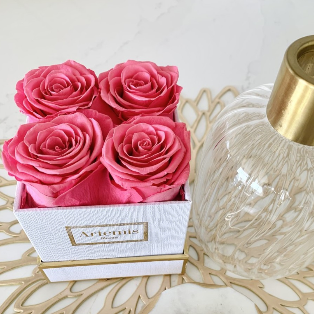 Dark pink roses in a white box on a gold metal plate charger